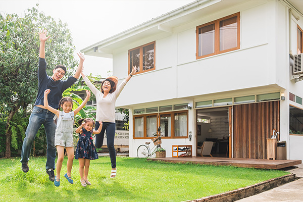 Familie springt vor Haus in die Luft vor Freude